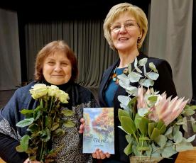 Aly­taus ap­skri­ties li­te­ra­tų klu­bo „Tėk­mė“ pir­mi­nin­kė Re­gi­na Ra­si­mie­nė sveikina al­ma­na­cho su­da­ry­to­ją Scho­las­ti­ką Ka­va­liaus­kie­nę. 